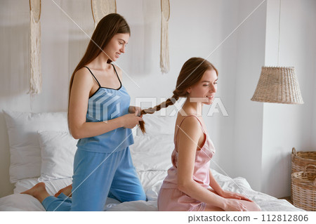 Older sister making hair to her younger female sibling 112812806