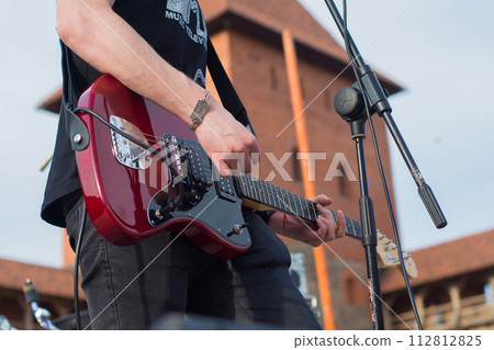 musician on stage playing red guitar, close-up 112812825