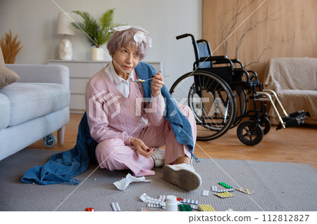 Senior woman with dementia mental disorder eating pills scattered on floor Senior woman with dementia mental disorder eating pills scattered on floor 112812827