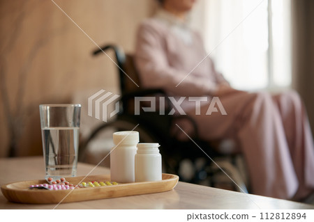 Medications and recovery pills with glass of water on table for old patient 112812894