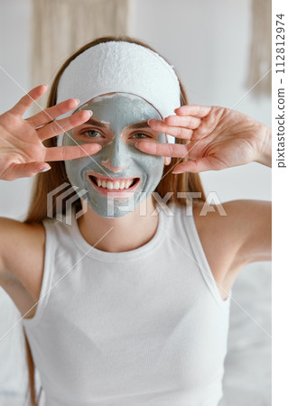 Young woman with clay facial cosmetology mask 112812974