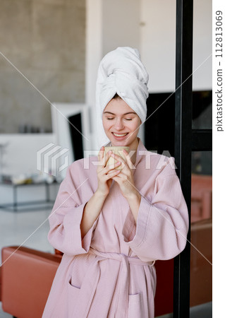 Pensive dreamy woman drinking morning coffee or tea after shower Pensive dreamy woman drinking morning coffee or tea after shower 112813069