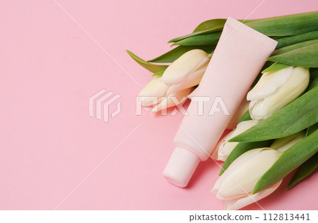 Beige cosmetic tube with cream or lotion for body and bouquet of white tulips on beige background 112813441