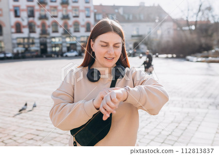 30s Beautiful young woman looking at the clock and waiting a friend or boyfriend, who is late in the street. Active lifestyle concept 112813837
