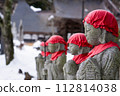 Japanese Jizo statues with red caps in a winter landscape. 112814038