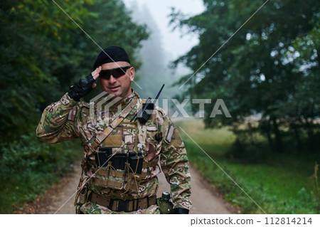 A dedicated soldier salutes his elite unit, showcasing camaraderie and readiness for the most perilous military operations A dedicated soldier salutes his elite unit, showcasing camaraderie and readiness for the most perilous military operations 112814214