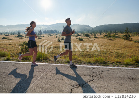 Energized by the beauty of nature, a couple powers through their morning run, their bodies and spirits invigorated. Energized by the beauty of nature, a couple powers through their morning run, their bodies and spirits invigorated. 112814230