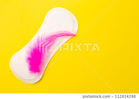 Blood and feminine hygiene pad with feather on yellow background. First menstrual period concept  112814298