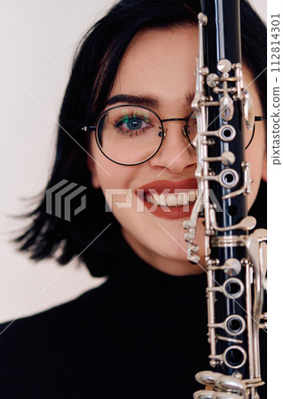 Graceful Brunette Musician Posing with Clarinet on White Background Graceful Brunette Musician Posing with Clarinet on White Background 112814301