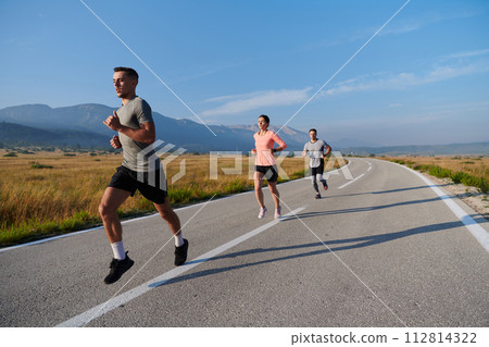 A group of friends maintains a healthy lifestyle by running outdoors on a sunny day, bonding over fitness and enjoying the energizing effects of exercise and nature 112814322