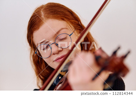 Stunning Redhead Musician Poses with Violin in Captivating Portrait 112814344