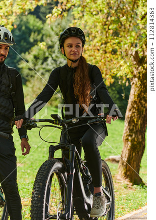 A sweet couple, equipped with bicycles and engrossed in coordinating their journey, checks their GPS mobile and watches while planning scenic routes in the park, seamlessly blending technology and A sweet couple, equipped with bicycles and engrossed in coordinating their journey, checks their GPS mobile and watches while planning scenic routes in the park, seamlessly blending technology and 112814363