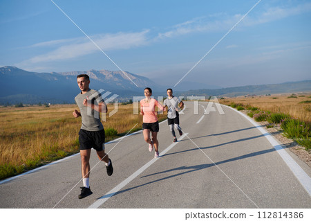 A group of friends maintains a healthy lifestyle by running outdoors on a sunny day, bonding over fitness and enjoying the energizing effects of exercise and nature 112814386