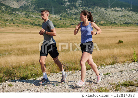 Energized by the beauty of nature, a couple powers through their morning run, their bodies and spirits invigorated. Energized by the beauty of nature, a couple powers through their morning run, their bodies and spirits invigorated. 112814388