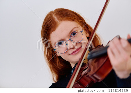 Stunning Redhead Musician Poses with Violin in Captivating Portrait 112814389