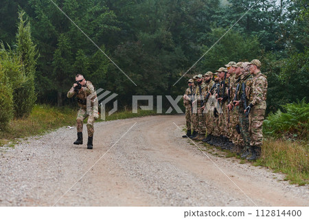 A major imparts precise military instructions to his elite unit, embodying strategic leadership as they gather for a briefing on tactical maneuvers and disciplined coordination 112814400