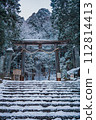 Long stone stairs covered with snow leading to a Japanese torii gate. 112814413