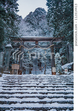 Long stone stairs covered with snow leading to a Japanese torii gate. Long stone stairs covered with snow leading to a Japanese torii gate. 112814413