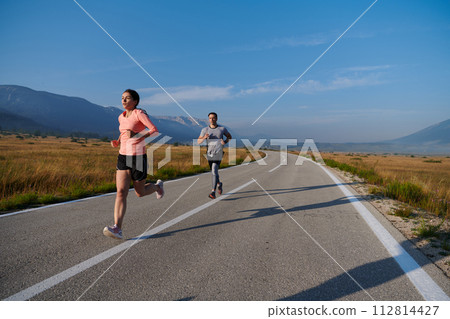 Energized by the beauty of nature, a couple powers through their morning run, their bodies and spirits invigorated. Energized by the beauty of nature, a couple powers through their morning run, their bodies and spirits invigorated. 112814427