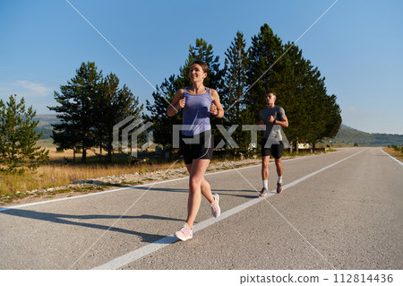 Energized by the beauty of nature, a couple powers through their morning run, their bodies and spirits invigorated. 112814436