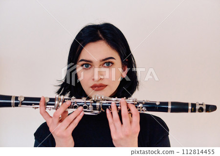 Graceful Brunette Musician Posing with Clarinet on White Background 112814455