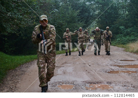 A group of elite soldiers leads captives through a military camp, showcasing a tense atmosphere of detention and security operations A group of elite soldiers leads captives through a military camp, showcasing a tense atmosphere of detention and security operations 112814465