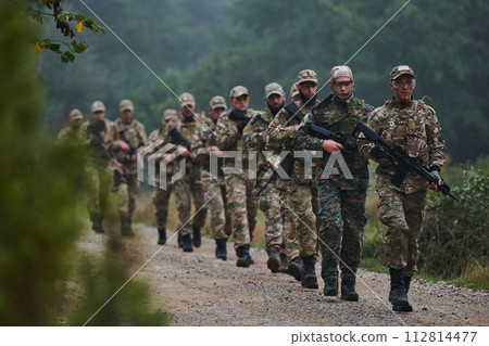 An elite military unit, led by a major, confidently parades through dense forest, showcasing precision, discipline, and readiness for high-risk operations An elite military unit, led by a major, confidently parades through dense forest, showcasing precision, discipline, and readiness for high-risk operations 112814477