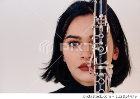 Graceful Brunette Musician Posing with Clarinet on White Background 112814479