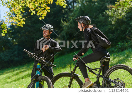 A sweet couple, equipped with bicycles and engrossed in coordinating their journey, checks their GPS mobile and watches while planning scenic routes in the park, seamlessly blending technology and A sweet couple, equipped with bicycles and engrossed in coordinating their journey, checks their GPS mobile and watches while planning scenic routes in the park, seamlessly blending technology and 112814491