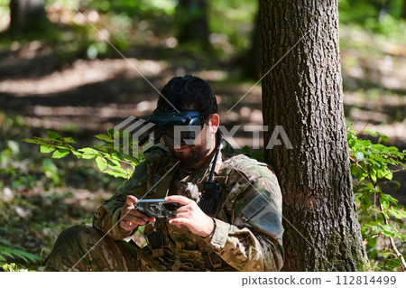 An elite soldier, equipped with state-of-the-art VR glasses, adeptly maneuvers a military drone, showcasing the seamless integration of cutting-edge technology in modern warfare 112814499