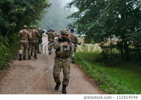 A group of elite soldiers leads captives through a military camp, showcasing a tense atmosphere of detention and security operations 112814549