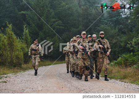 An elite military unit, led by a major, confidently parades through dense forest, showcasing precision, discipline, and readiness for high-risk operations An elite military unit, led by a major, confidently parades through dense forest, showcasing precision, discipline, and readiness for high-risk operations 112814553