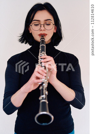 Graceful Brunette Musician Posing with Clarinet on White Background 112814610