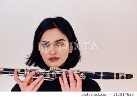 Graceful Brunette Musician Posing with Clarinet on White Background 112814626