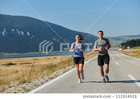 Energized by the beauty of nature, a couple powers through their morning run, their bodies and spirits invigorated. Energized by the beauty of nature, a couple powers through their morning run, their bodies and spirits invigorated. 112814918