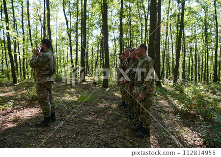 A dedicated group of soldiers engages in Islamic prayer amidst the challenging and perilous conditions of a military operation in dense forested areas 112814955