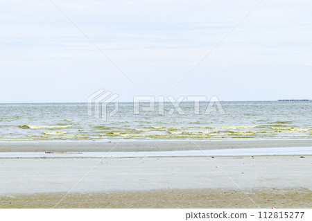 Green dark sea water wave natural phenomenon with brown sand beach. Seawater in Bang Saen, Chonburi Province, has turned green. Natural phenomenon. During rainy season called Plankton bloom 112815277