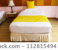 White bed with stripes morning sunlight shines in from sides. Comfortable bed with soft white mattress, pillows indoors, yellow blanket. Small bed can only accommodate one person in hotel or apartment 112815494