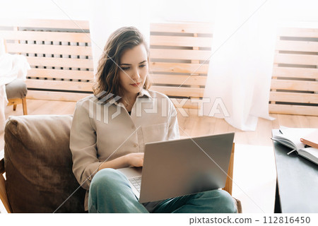 Modern Home Office. Woman Seriously Working on Laptop in Living Space. Efficient Remote Work. Woman Modern Home Office. Woman Seriously Working on Laptop in Living Space. Efficient Remote Work. Woman 112816450