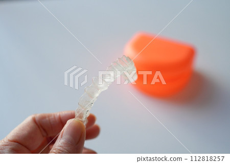 Woman's hand holding orthodontic mouthpiece Invisalign 112818257
