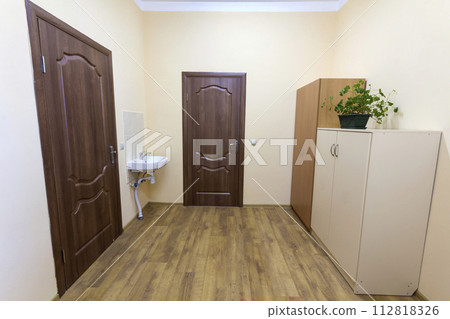 Light empty corridor hall with wooden floor, brown doors and sink. School, office or clinic interior. 112818326