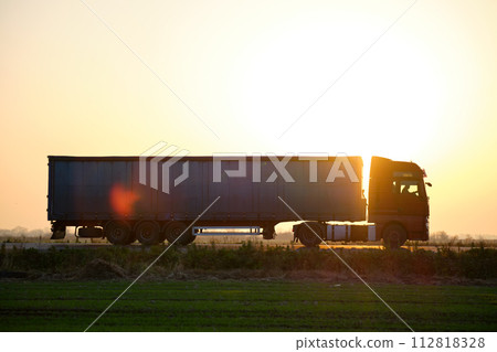 Semi-truck with cargo trailer driving on highway hauling goods in evening. Delivery transportation and logistics concept Semi-truck with cargo trailer driving on highway hauling goods in evening. Delivery transportation and logistics concept 112818328