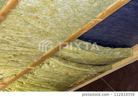 Thermal insulation mineral rock wool installation at the new building attic ceiling 112818356