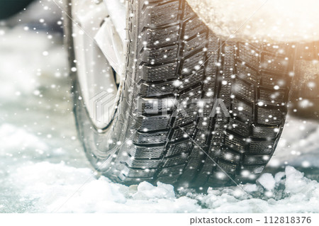 Close-up of car wheel in winter tire on snowy road Close-up of car wheel in winter tire on snowy road 112818376