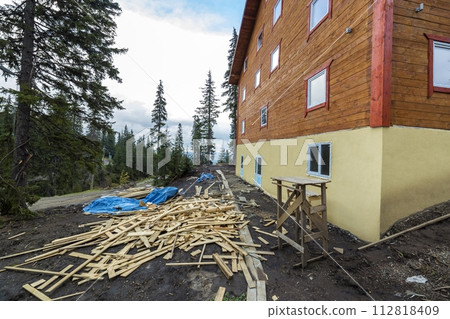 Two story wooden house cottage made of boards and logs on blue sky background. 112818409