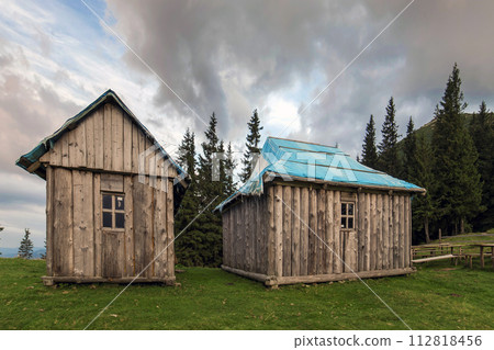 Old wooden shepherd huts on mountains green valley on blue cloud 112818456