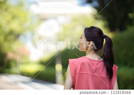 穿著運動服穿過綠樹的年輕女子 穿著運動服穿過綠樹的年輕女子 112819268