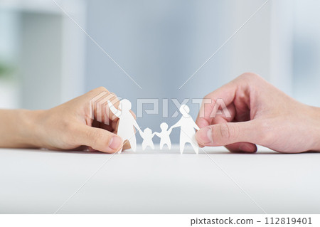 A couple's hands holding a family paper cutout 112819401