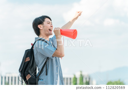 A young Asian man, college student, high school student, and student cheering, cheering, and cheering through a megaphone under the blue sky. A young Asian man, college student, high school student, and student cheering, cheering, and cheering through a megaphone under the blue sky. 112820569