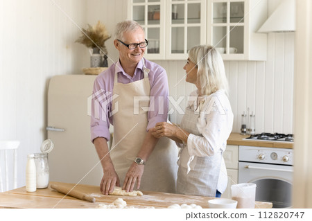Elderly father and mature daughter cooking together in the kitchen Elderly father and mature daughter cooking together in the kitchen 112820747